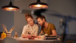 "Stijlvolle LED-hanglampen die een warme gloed verspreiden over twee mensen die samenwerken, en energiezuinige verlichting tonen voor productieve avondtaken."