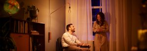 "Lampe de sol à ampoule DEL de style rétro créant une ambiance chaleureuse pour la conversation du couple en soirée, mettant en valeur un éclairage d’ambiance écoénergétique dans un salon confortable. »