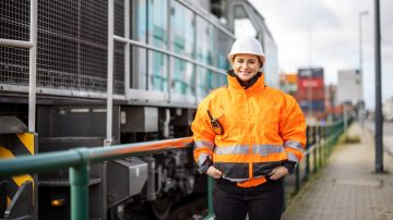Woman in construction hat in front of train