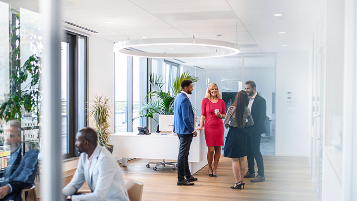 Business executives enjoying conversation with diverse colleagues in office