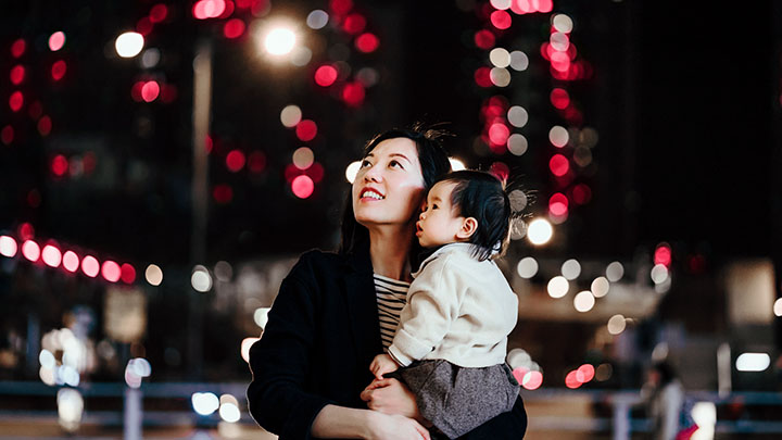 Mother and baby looking up while walking in city at night