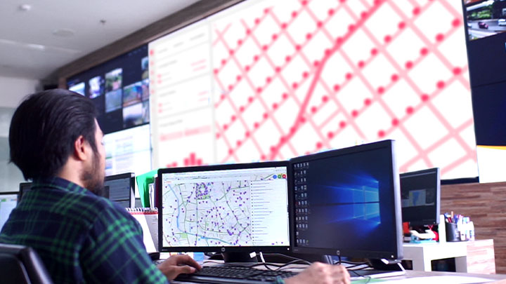 A worker inside of a control room, looking at large monitors