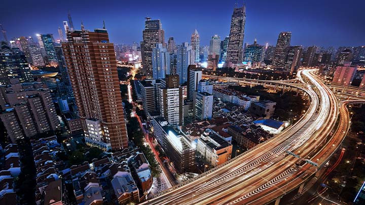 An overhead view of a highway running through the city, at night