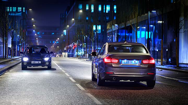 Two cars passing each other at night in a city