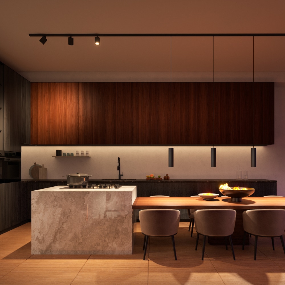 Track lighting fixtures mounted on the kitchen ceiling illuminate the island and dining area, highlighting surfaces and seating.
