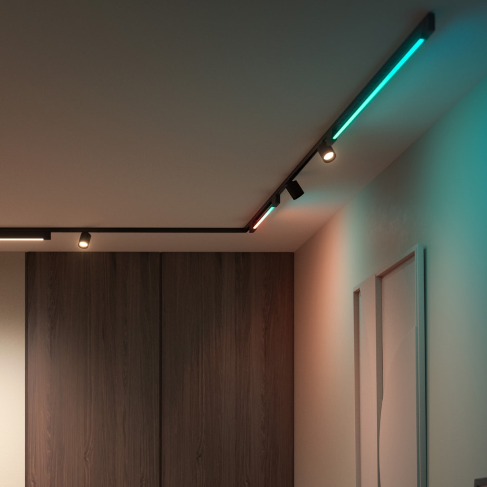 Ceiling-mounted track lighting system with linear and spot fixtures emitting colored and white light onto adjacent walls and surfaces.