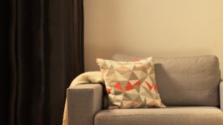 Salon confortable avec lampe de table LED moderne, éclairant un canapé gris et créant une ambiance chaleureuse pour la détente à la maison.