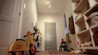 Entrée lumineuse avec éclairage LED encastré illuminant les étagères, les jouets et un vélo d'équilibre pour enfants.