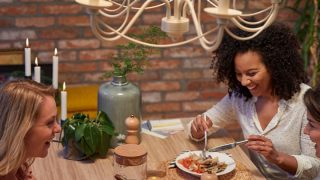 Cuisine moderne avec lumières suspendues DEL de style rétro illuminant deux femmes profitant du dîner, créant une atmosphère chaleureuse et accueillante.