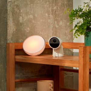 Une lampe et une caméra Hue Secure sur un meuble en bois.