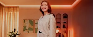 Une femme se tient dans un salon éclairé par des lampes Philips Hue.