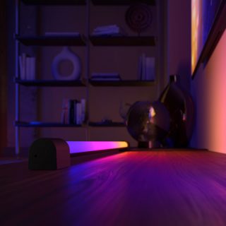 Un Play light tube dégradé, placé sous un écran de télévision et diffusant une lumière rose, violette et jaune. 
