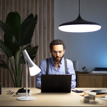 Homme assis devant un ordinateur portable à un bureau avec deux lampes connectées