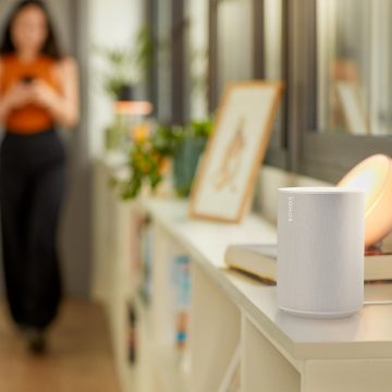 Une enceinte connectée Sonos est posée sur une table de chevet et des lampes et spots connectés Philip Hue éclairent la pièce.