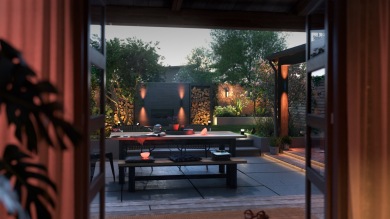 Un jardin et un patio sont magnifiquement éclairés par les tons chaleureux de l'applique connectée disponible avec les offres d'éclairage connecté dédié à l'extérieur.