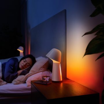 Een vrouw slaapt in bed bij een gedimde slimme bedlamp met rood en oranje licht