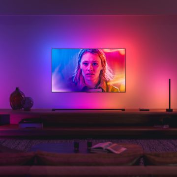 LG-tv hangend aan de muur in de woonkamer omgeven door gekleurde lampen