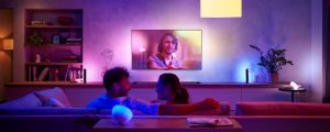Man en vrouw die op de bank zitten voor een LG-tv en worden omgeven door paarse en blauwe Hue verlichting
