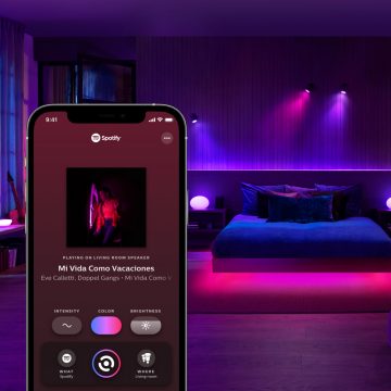 Slaapkamer met slimme tafellampen en slimme spots met een mobiel apparaat met daarop het tabblad Synchroniseren in de Hue app