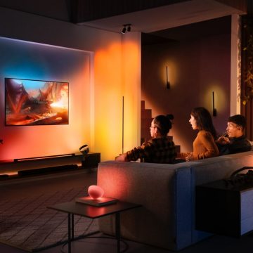 Drie mensen die op een bank tv kijken met surroundverlichting.