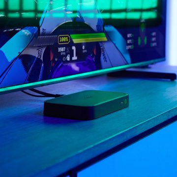 A HDMI Sync box 8K sits on a TV console in a room with blue entertainment lighting.