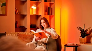 Une femme lit un livre sur le divan, avec des lampes Hue derrière elle.
