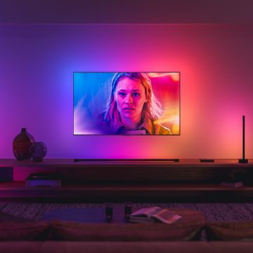 Un téléviseur synchronisé avec l’éclairage ambiant Philips Hue s’illumine dans des tons bleus, roses et rouges correspondant à l’image à l’écran.