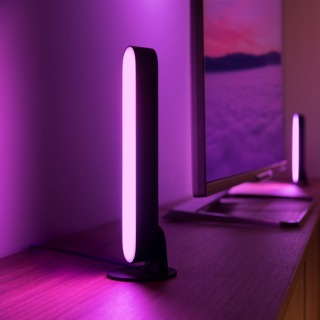 Deux barres lumineuses Play placées de chaque côté d’un écran de télévision brillent d’une lumière intelligente rose.