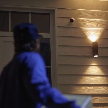Livreur marchant jusqu'à une porte d'entrée protégée par la caméra Philips hue Secure
