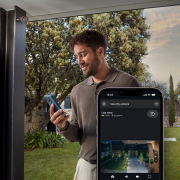 Un homme surveille la vue en direct d’un jardin sur son téléphone intelligent avec l’application Hue.