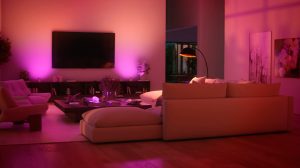 Un espace télévision dans un salon aux murs baignés d’une lumière intelligente aux tons roses et violets