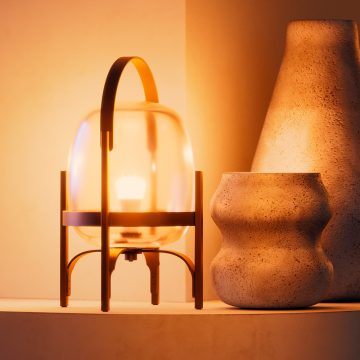 Une ampoule intelligente A19 est installée sur une lampe de table en verre qui brille d’une lumière intelligente blanche et chaleureuse.