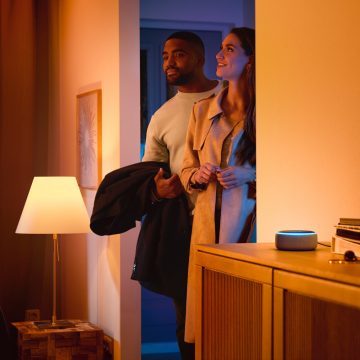 Hombre y mujer entrando en una casa con un altavoz inteligente 