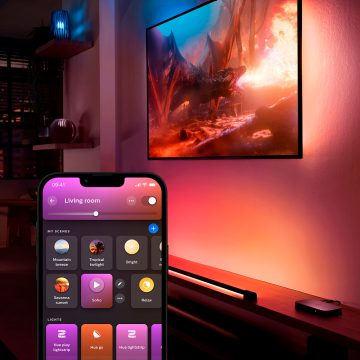 En TV-surroundbelysning som lyser i blått och rosa toner och styrs av Hue app och visar olika ljusscener.