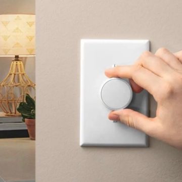Hand som vrider ratten på en vit smart strömbrytare på väggen