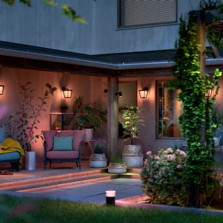 En uteplats i trädgården upplyst med smart Philips Hue-utomhusbelysning som lyser i varmvita och rosa toner