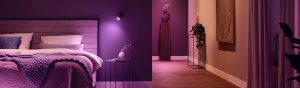 Bedroom with soft ambient purple lighting, wooden headboard, cozy bedding, side table, and hallway with decorative accents.