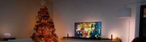 Smart lighting products placed near a television and on a shelf, casting colored light onto the wall and surroundings.