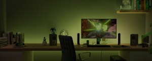 Gaming room desk with smart light bars placed beside monitor, casting green light onto wall and workspace, monitor displaying game.
