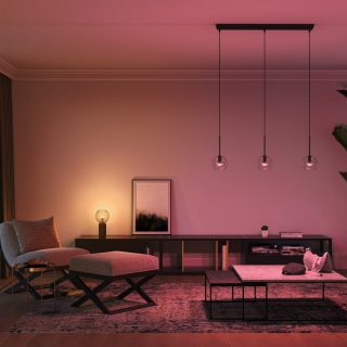 Pendant smart lights with glass shades suspended from ceiling, illuminating living room area with adjustable colored lighting.
