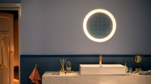 Round illuminated bathroom mirror mounted above a sink, casting bright light onto the countertop and surrounding fixtures.