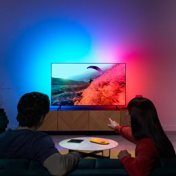 Un couple profite de la lampe à DEL pour la télévision grâce à des couleurs synchronisées avec l’écran.