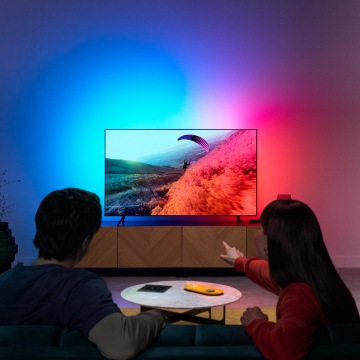Pár, který si užívá TV LED světlo s barvami synchronizovanými s obrazovkou.